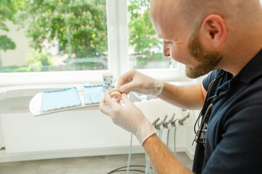 Ein Zahnarzt hält eine Gebissmodell für Zahnersatz in der Hand