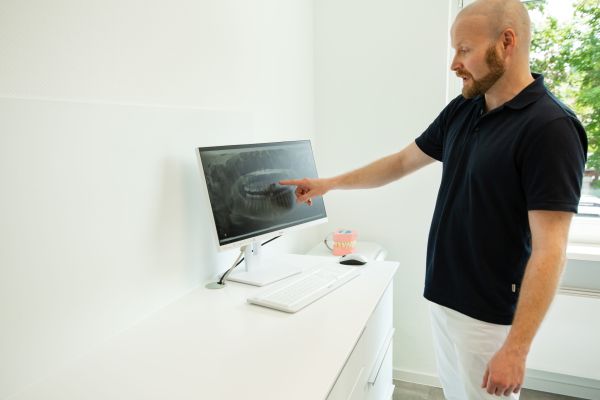 Ein Zahnarzt erklärt eine digitale Röntgenaufnahme am Bildschirm in der Praxis