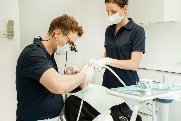 Zahnarzt und Assistenz bei der Behandlung eines Patienten im modernen Behandlungszimmer