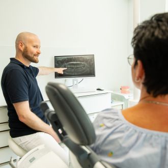 Zahnarzt erklärt Patientin etwas am Bildschirm in einer Zahnarztpraxis